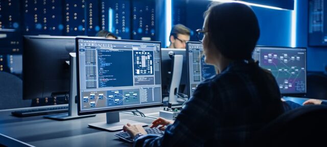 Smart Female IT Programer Working on Desktop Computer in Data Center System Control Room. Team of Young Professionals Doing Code Programming